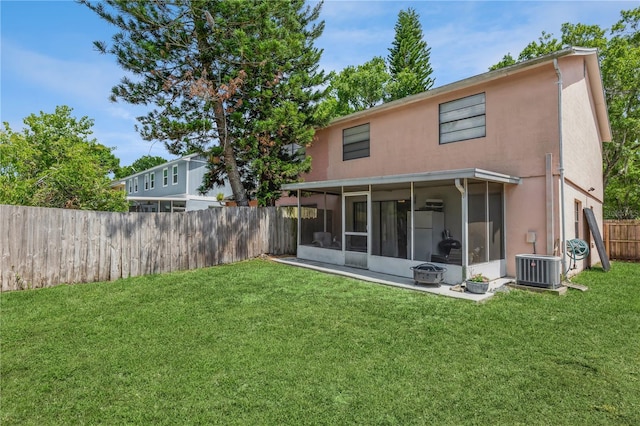 rear view of property with a sunroom, cooling unit, and a yard