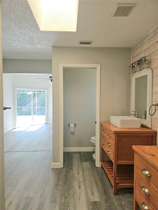 bathroom featuring hardwood / wood-style floors, ceiling fan, toilet, and a textured ceiling