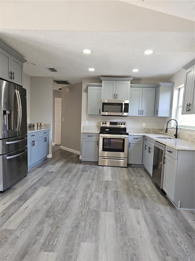 kitchen with stainless steel appliances, gray cabinets, and sink