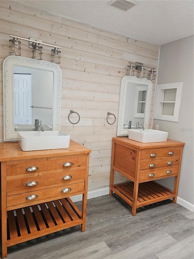 bathroom with wooden walls, hardwood / wood-style floors, and a textured ceiling