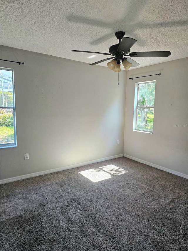 carpeted empty room featuring ceiling fan, a textured ceiling, and a wealth of natural light