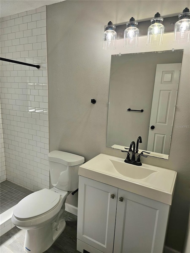 bathroom with tiled shower, vanity, and toilet