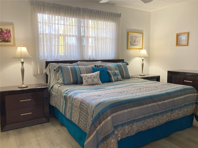 bedroom featuring ceiling fan, light hardwood / wood-style flooring, and a textured ceiling