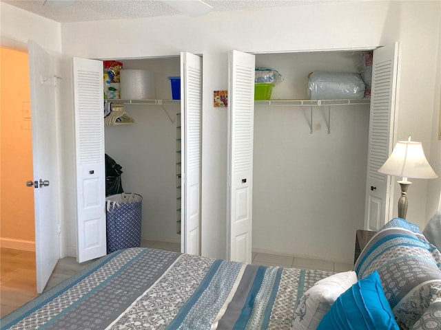 bedroom featuring a textured ceiling, two closets, and light wood-type flooring