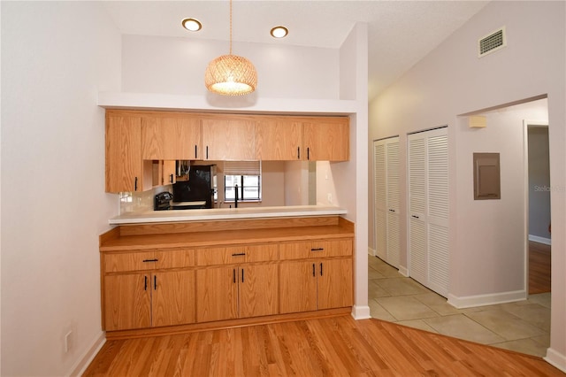 kitchen featuring decorative light fixtures, light tile patterned floors, electric panel, and vaulted ceiling