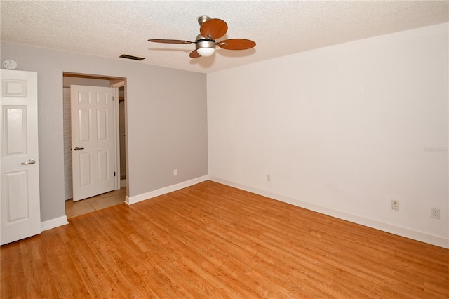 unfurnished room with ceiling fan, a textured ceiling, and light hardwood / wood-style flooring