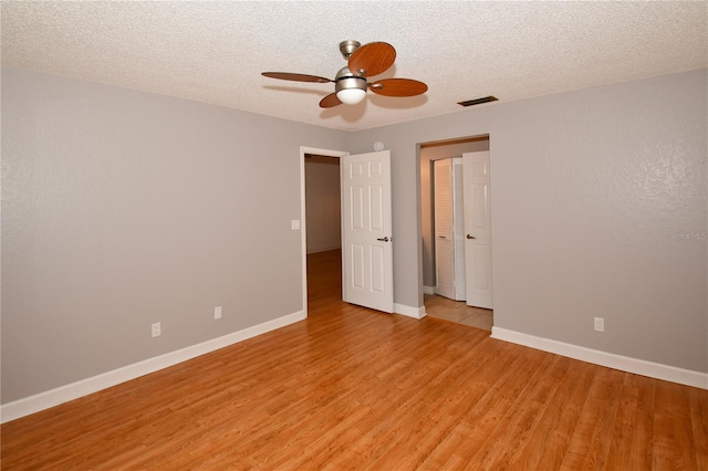 unfurnished bedroom with ceiling fan, a textured ceiling, and light wood-type flooring