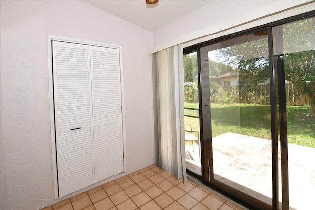 doorway to outside with vaulted ceiling and light tile patterned flooring