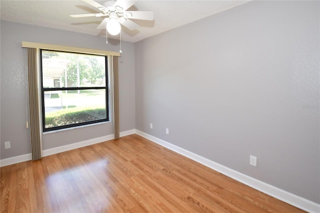 empty room featuring ceiling fan, light wood-type flooring, and a textured ceiling