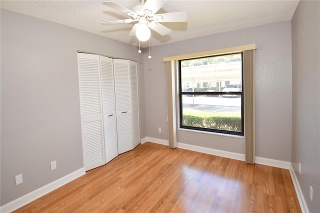 unfurnished bedroom with ceiling fan, a closet, a textured ceiling, and multiple windows