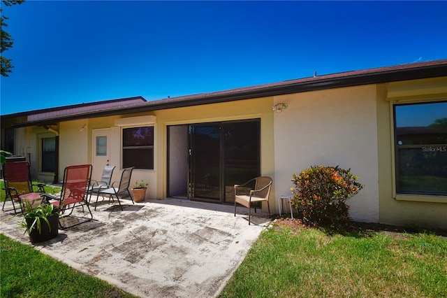 back of property featuring a lawn and a patio