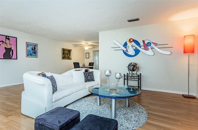 living room featuring hardwood / wood-style floors, ceiling fan, and a textured ceiling