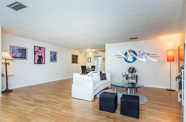 living room with a textured ceiling, light hardwood / wood-style flooring, and ceiling fan