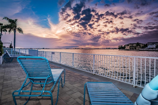 patio terrace at dusk featuring a water view