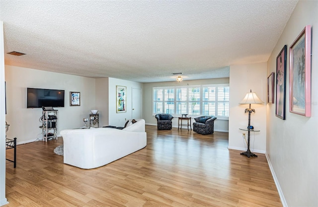 living room with a textured ceiling and light wood-type flooring