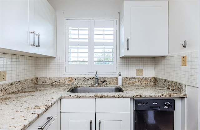 kitchen with light stone counters, sink, white cabinetry, and black dishwasher