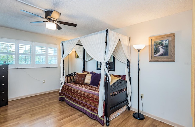 bedroom with hardwood / wood-style floors, ceiling fan, and a textured ceiling