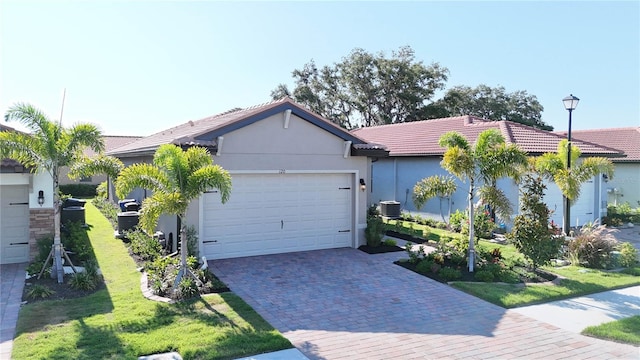 ranch-style home featuring a front yard, a garage, and central air condition unit