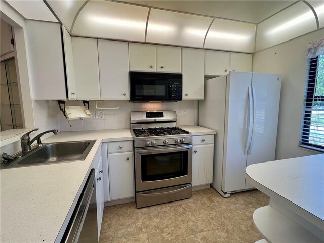 kitchen featuring white cabinets, light tile flooring, backsplash, appliances with stainless steel finishes, and sink