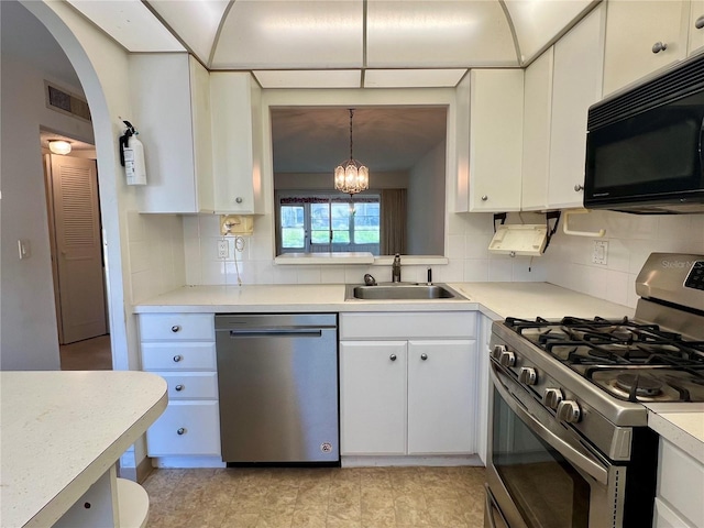 kitchen with backsplash, appliances with stainless steel finishes, light tile floors, and decorative light fixtures