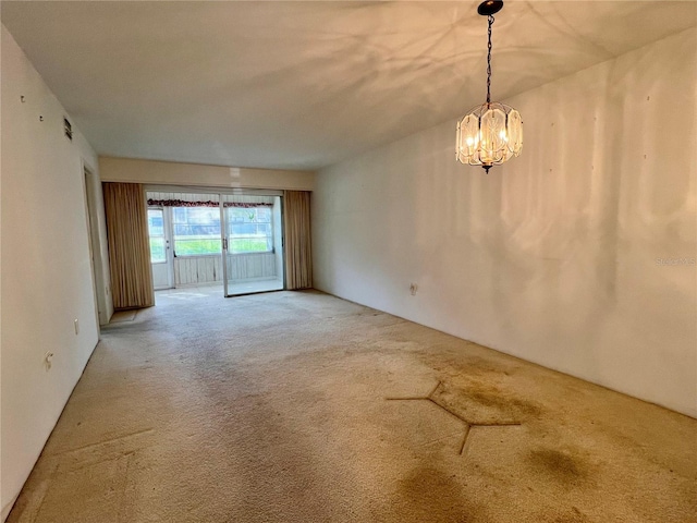 empty room with carpet floors and an inviting chandelier