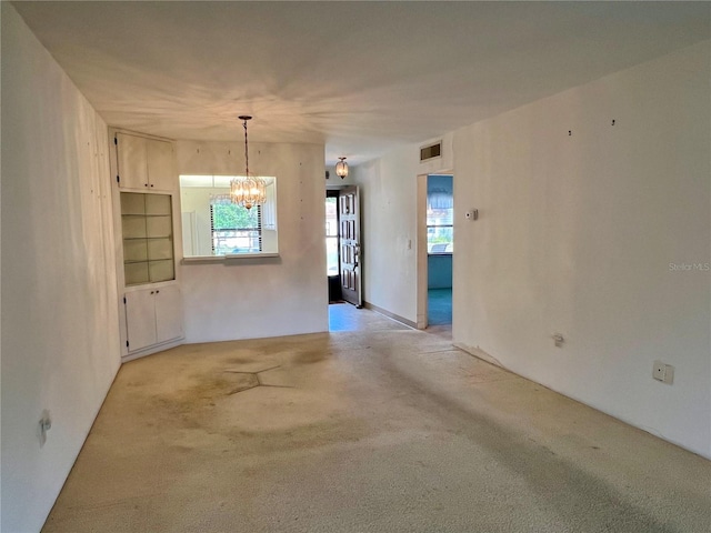 interior space featuring built in features, an inviting chandelier, and light colored carpet