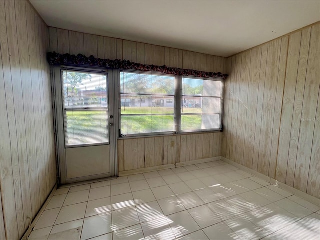 spare room featuring wood walls, plenty of natural light, and light tile floors