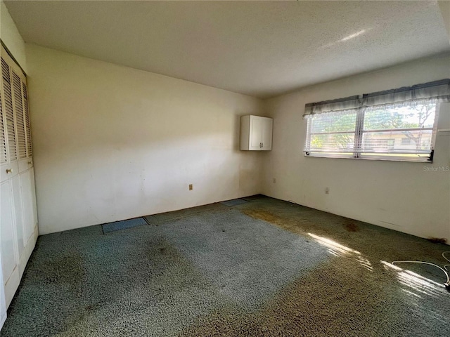 empty room with a textured ceiling and dark colored carpet