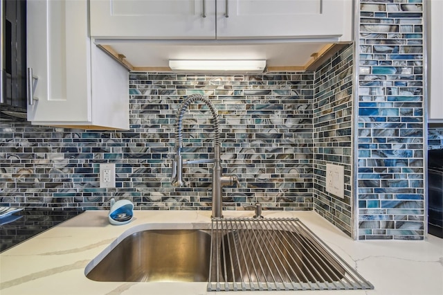 kitchen featuring white cabinetry, light stone countertops, sink, and tasteful backsplash