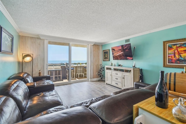 living room featuring a textured ceiling, wood finished floors, visible vents, and crown molding