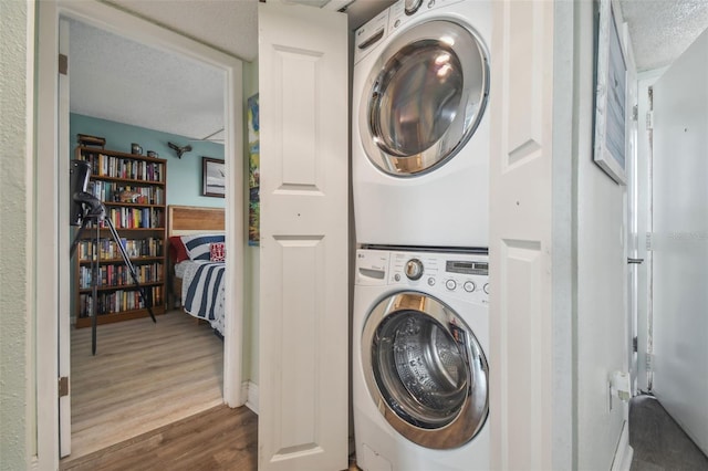 clothes washing area with dark hardwood / wood-style flooring, a textured ceiling, and stacked washer and clothes dryer