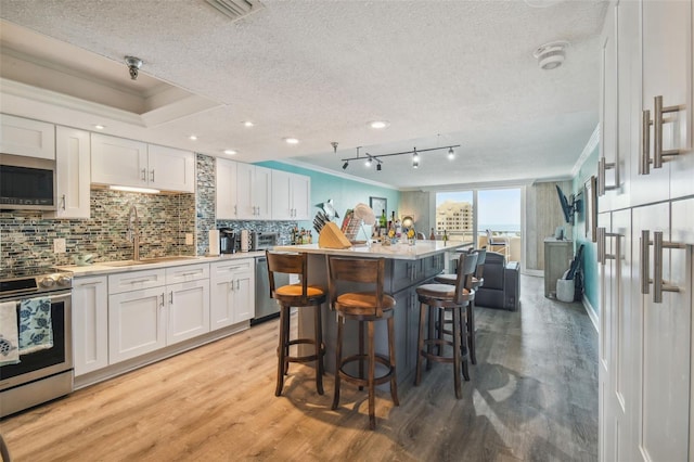 6035 Sea Ranch Dr Unit 505, Hudson, FL 34667 - kitchen featuring stainless steel appliances, ornamental molding, a textured ceiling, white cabinets, and light wood-style floors