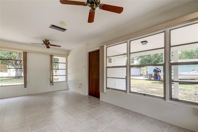 tiled empty room with a wealth of natural light and ceiling fan