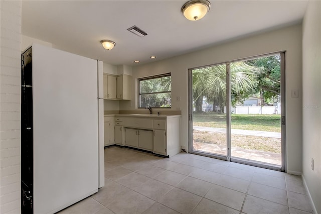 kitchen featuring light tile patterned floors, white fridge, a wealth of natural light, and sink