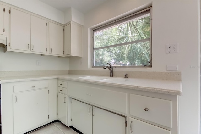 kitchen with white cabinets, light tile patterned flooring, and sink