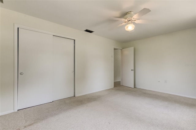 unfurnished bedroom with ceiling fan, light colored carpet, and a closet