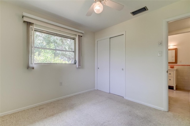 unfurnished bedroom with light colored carpet, a closet, and ceiling fan