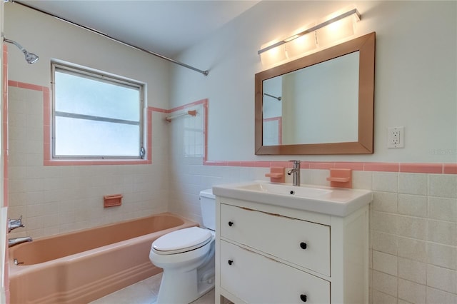 full bathroom with vanity, tile patterned floors, tiled shower / bath, toilet, and tile walls