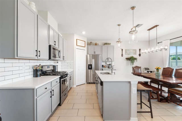 kitchen featuring sink, pendant lighting, a kitchen island with sink, a breakfast bar, and appliances with stainless steel finishes