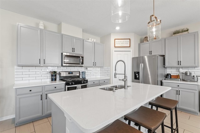 kitchen featuring a breakfast bar, a kitchen island with sink, sink, and stainless steel appliances