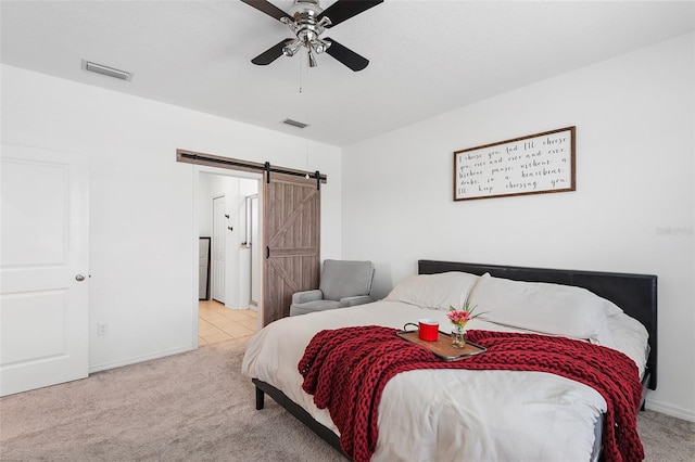 carpeted bedroom featuring a barn door and ceiling fan