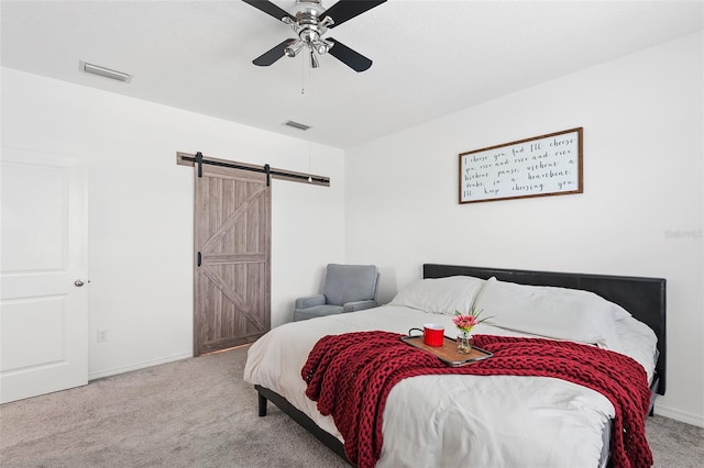 bedroom featuring ceiling fan, a barn door, and carpet floors