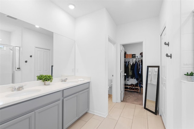 bathroom with tile patterned flooring, vanity, toilet, and a shower with shower door