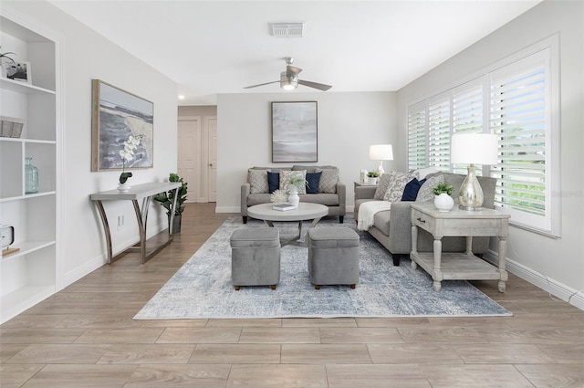 living room featuring built in features, a wealth of natural light, and ceiling fan