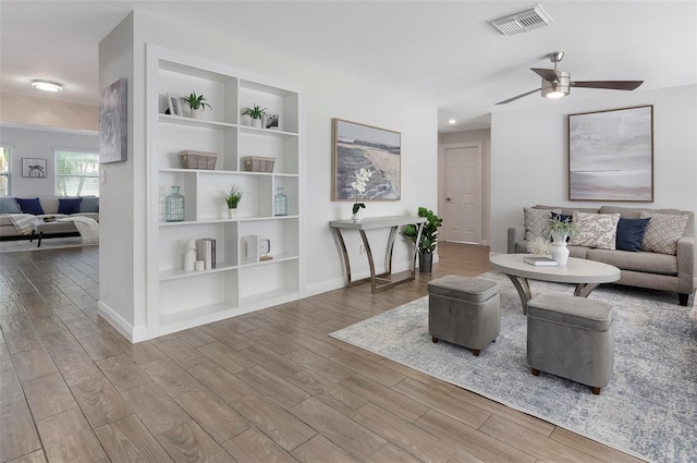 living room featuring built in shelves and ceiling fan