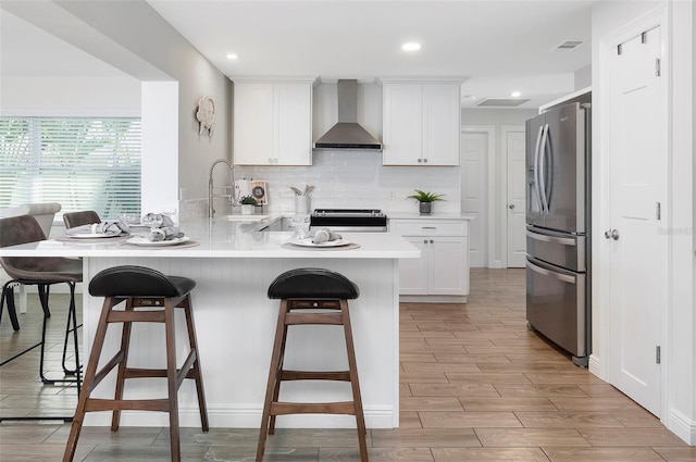 kitchen featuring backsplash, stainless steel appliances, sink, wall chimney range hood, and white cabinetry