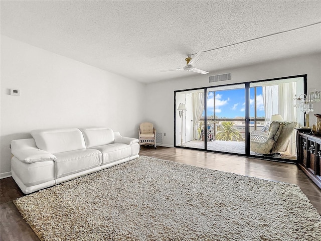 living room with a textured ceiling, dark hardwood / wood-style floors, and ceiling fan