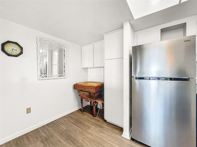 kitchen with white cabinets, stainless steel fridge, and light wood-type flooring