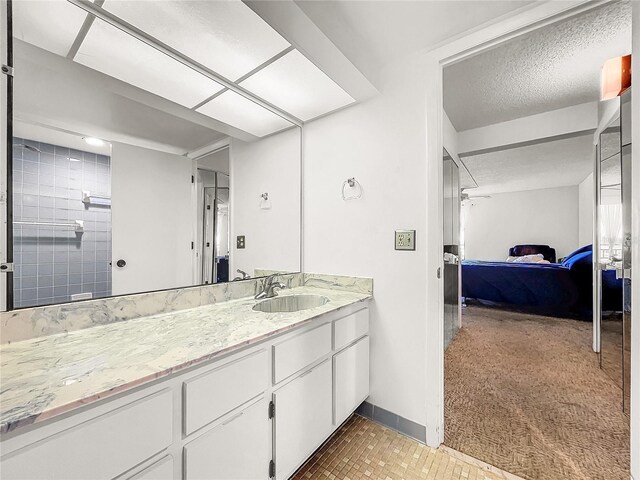 bathroom with tile patterned flooring, vanity, a textured ceiling, and tiled shower