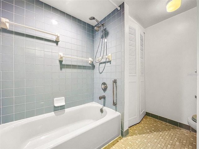 bathroom featuring tiled shower / bath, tile patterned floors, and toilet